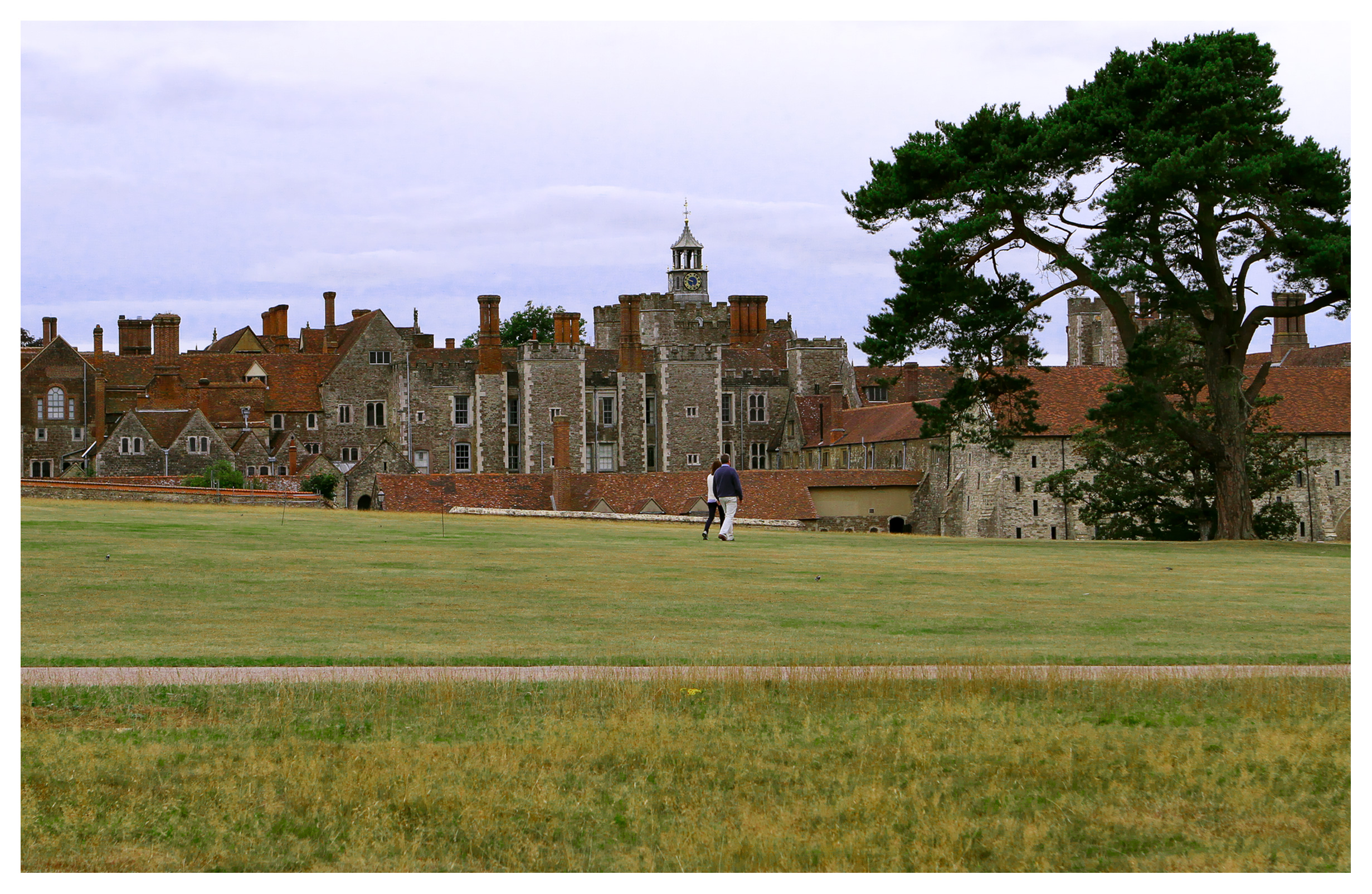 Couple walking on the grounds of Knole Park, Sevenoaks, Kent, England, with Knole House in the background