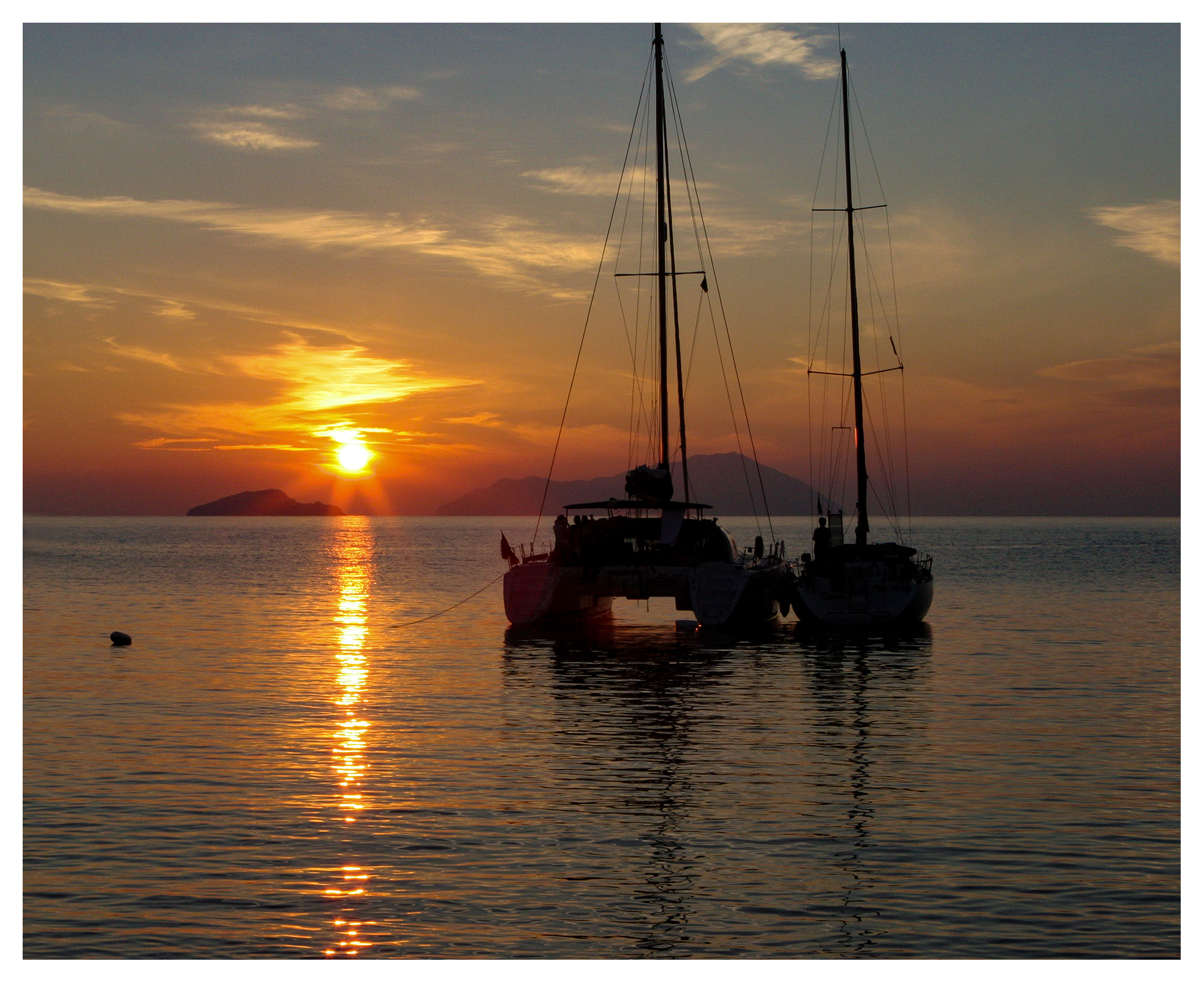 Yachting photography: Monohull and catamaran anchored together in a glorious sunset near cape Sounio, Greece
