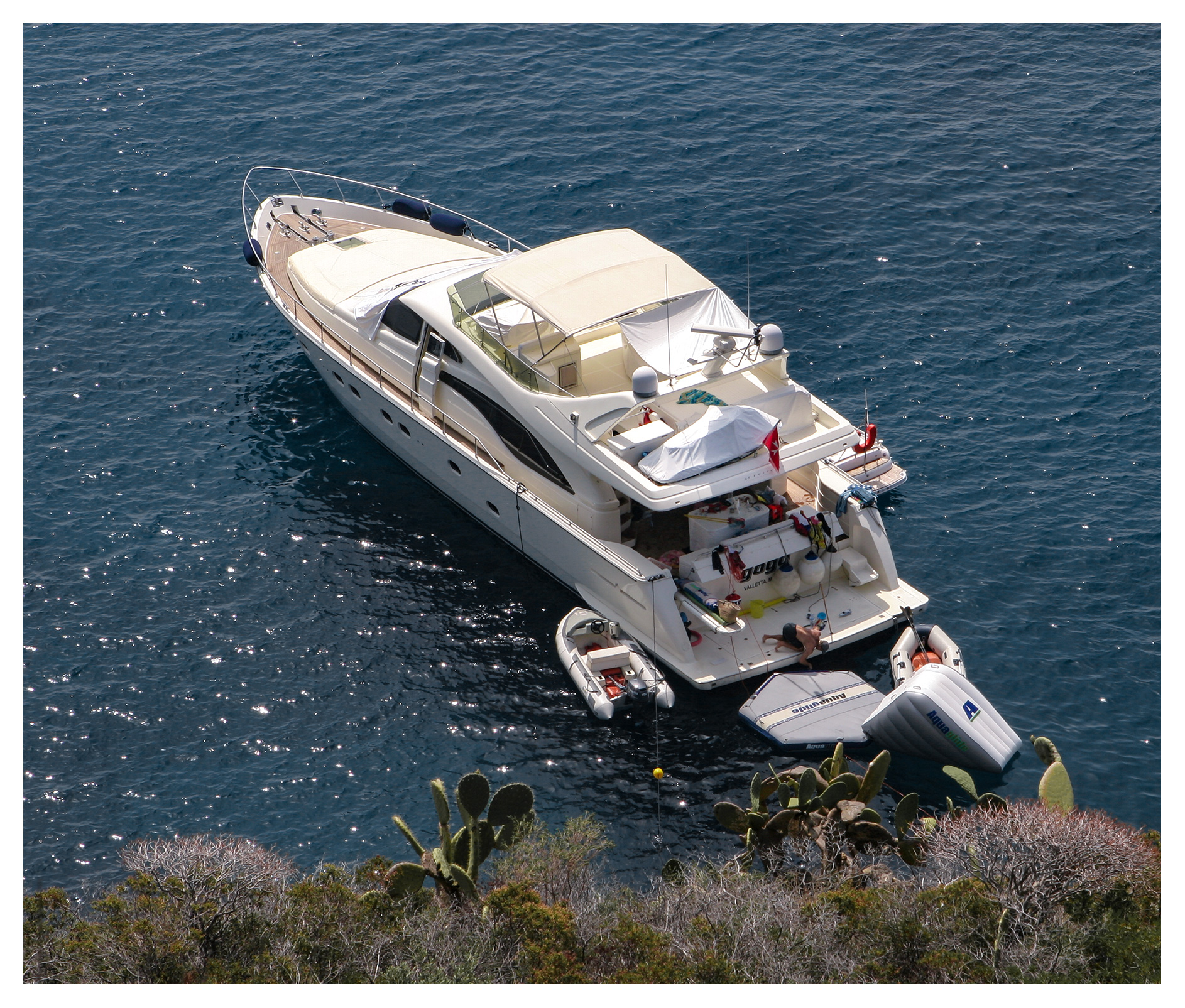 Skipper working on his motor yacht, anchored off Capo Milazzese, Panarea, Aeolian islands, Sicily