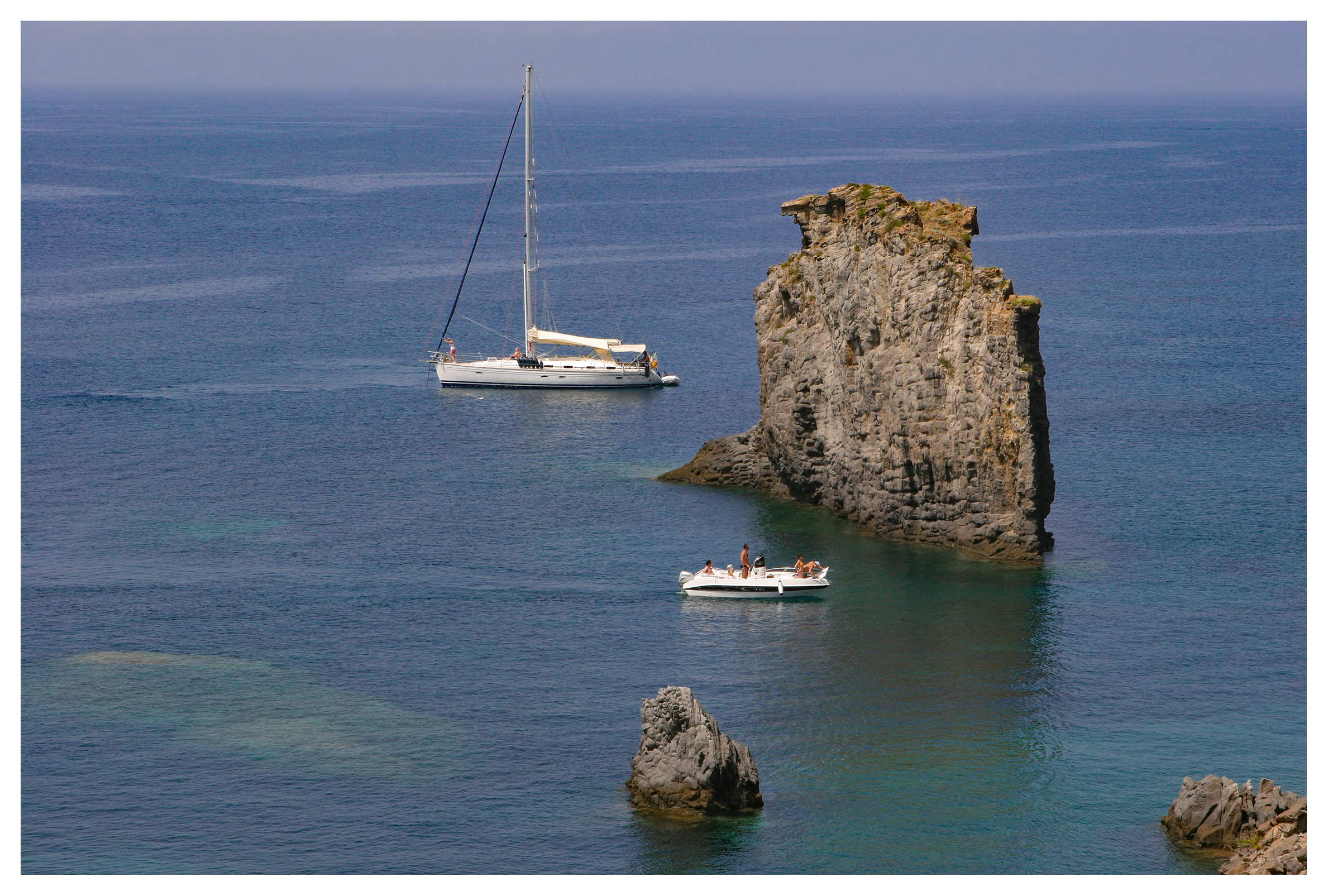 Boats in clear waters in Cala Junco, Panarea, Aeolian islands, Sicily